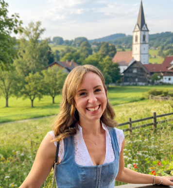 Vanessa Färber, Mama und Gründerin von Bärenschmausi Lächelnde Gründerin von Bärenschmausi steht auf einer Terrasse im Dirndl.